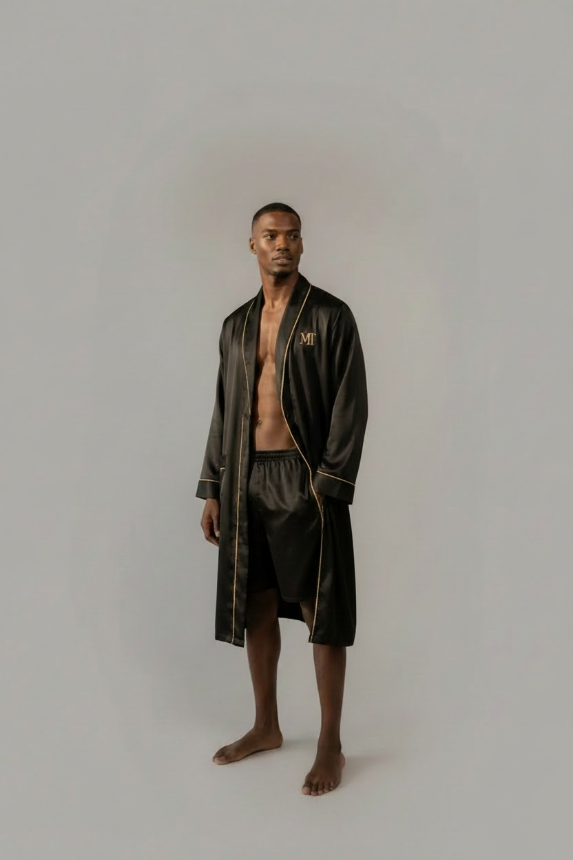 Man wearing a black robe and shorts in a room with large windows and another man in the background.